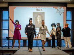 Jayme Ganey holds her arm in the air as school leaders and students walk the runway.