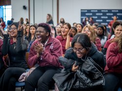 Conference attendees laugh and applaud in response to a fashion show.