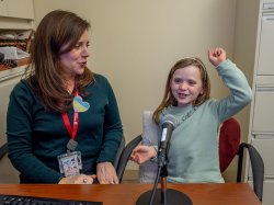 Colette raises an arm in celebration during her speech therapy session under the guidance of Alexis Gallagher.