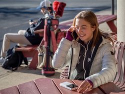 Olga Mikutina talks on a cell phone while seated outdoors.