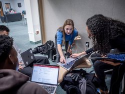 Olga Mikutina points to a laptop while working with three other students.