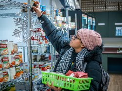 A student reaches for a food item to add to her basket of items.