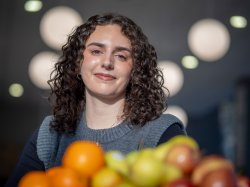 Allison Abrom smiles behind fruit in the foreground.