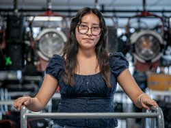 Pamela Hernandez stands in a campus broadcast media lab, surrounded by professional studio lights and equipment.