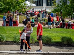 Casey Coleman pauses to talk with a colleague and young child holding a balloon animal.