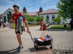 As the event winds down, Casey Coleman pulls a wagon full of supplies across the chalk‑covered sidewalk.