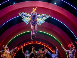Leilani Ford, in a butterfly costume, flies above fellow cast members onstage.