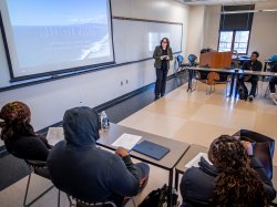 Ana Barahona stands at the front of a Montclair classroom as an assistant, looking at a whiteboard while teaching the class.