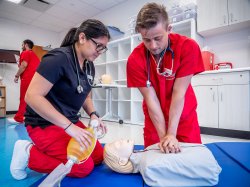Nursing students performing CPR on medical manikin in simulation lab.