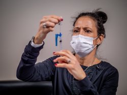 RN to BSN student in protective face mask filling a syringe.