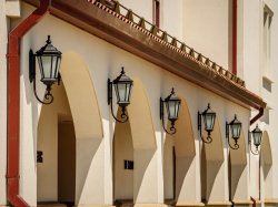 Four lamps in a row against one of the buildings on campus
