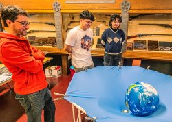 Physics majors Renzo Herrera and Stephanie Montoya with Professor Marc Favata setting up their curved spacetime demo.