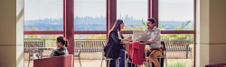 students talking and sitting infront of windows with NYC skyline in background
