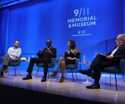 photo of panelists sitting on a stage. the 9/11 Memorial and Museum logo appears projected on a screen behind them.