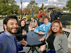 A photo of Montclair State University president Jonathan Koppell seated outside with students