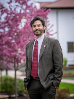 Montclair State University President Jonathan Koppell poses by a blooming tree on campus.