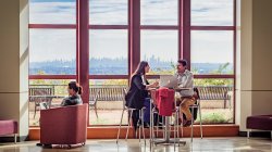 Photo of students studying in front of windows with the New York City skyline