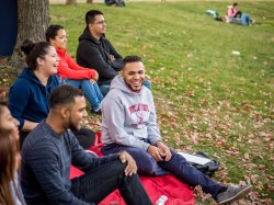 Photo of students sitting under a tree on campus.