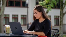 Student sitting at a table outside on a laptop.