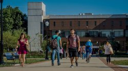 Students walking along the path in front of the CELS building on a sunny day.