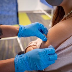 Close up view of student getting band-aid put on her shoulder after having received her vaccination shot