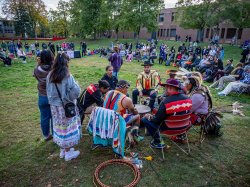 Red Blanket Singers in a circle with crowd watching in background