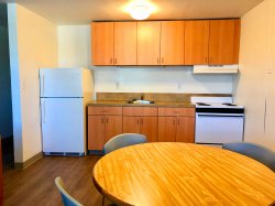 Another view of the kitchen in a Hawk Crossings apartment with a kitchen table and chairs as well as a fridge and stove.