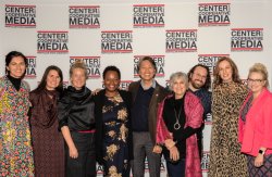 A group of 10 people in front of a branded back drop happy and smiling