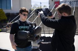 Two college students standing outside holding and testing broadcast equipment
