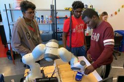 students using a robotic arm in the CRoSS lab