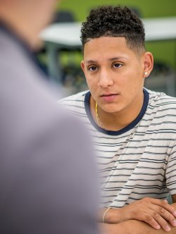 Photo of a male student listening in a classroom setting.