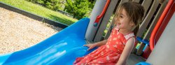 Image of a child about to slide down a slide on playground equipment.