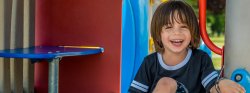 Image of a smiling child sitting on playground equipment.
