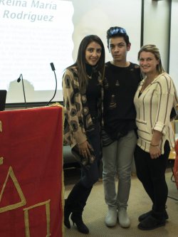 Photo of three students standing together at an event with a Cuban poet.