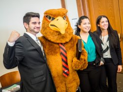 Rocky the Red Hawk with students in business attire