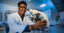 student in laboratory using binocular microscope