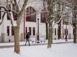 Student walking along the pathway next to the Student Center Quad in the snow.
