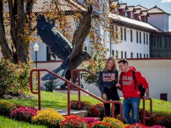 Two students talking next to the red hawk statue