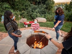 Student roasting marshmellows over a fire pit on campus.