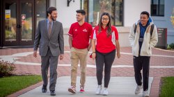 Koppell walking with three students on campus