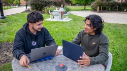 two students with laptops sitting and chatting