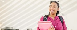 Picture of a student holding textbooks in a classroom