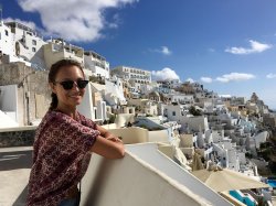 Student posing on balcony in Grecian cliffside town