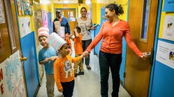 Photo of teacher with young students in a school hallway.