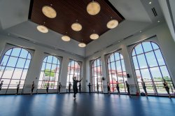 Dancers practicing in front of large windows in large dance studio