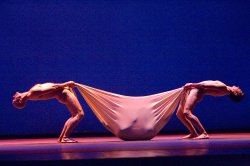 Photo of two dancers holding a third in a sling between them.