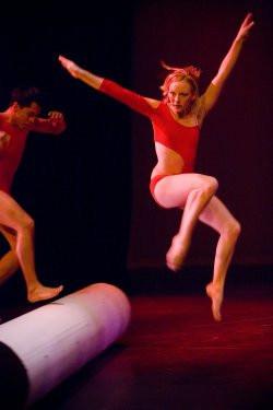 Photo of dancers in leotards jumping over a stage decoration