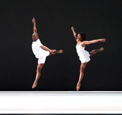 man and woman dressed in white dancing on stage in unison