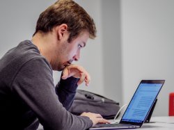 long photo of male student reviewing a document on a laptop