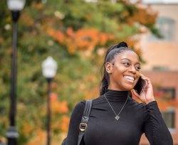 Student making phone call on mobile under fall foliage